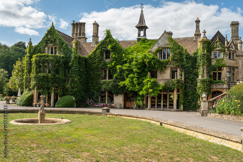 Quadro su tela Ivy-covered manor house with a fountain and lawn in the picturesque Castle Combe