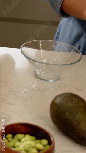 Vertical video: Starting meal prep, denim-clad cook slicing red pepper on cutting board with knife