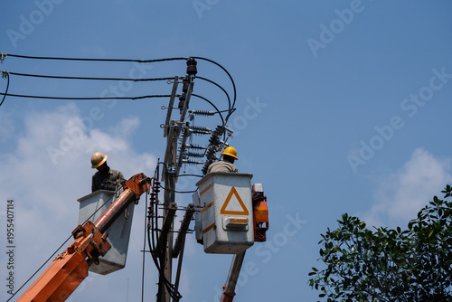 Canvas Print Two electrical workers repairing power lines on utility pole, wearing safety hel