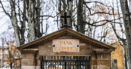 Close view of cemetery gate with cross and inscription in winter setting.