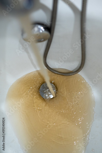 Dirty Rusty Water Flowing from Tap into Bathtub Drain Close Up Concept of Plumbing Issues at Home