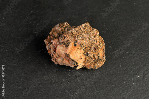 Billede på lærred Close-up of a rough, textured mineral specimen with pinkish and brown hues on a