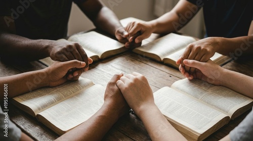 Praying, hands, Bible, group, diversity, community, faith, a diverse group of people holding hands in a circle over open Bibles on a wooden table during a church Bible study session.