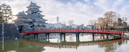 Tableau sur toile Panoramic View of Matsumoto Castle with Red Bridge Reflections