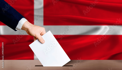 Hand placing a ballot in ballot box with the Danish flag in the background. Denmark Parliamentary vote 2026