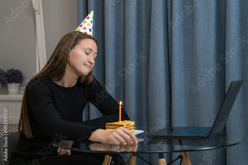 Sad woman wearing a party hat, gazing at a small birthday cake with a single lit candle while sitting alone at a table in her home, reflecting on feelings of isolation and loneliness