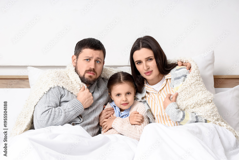 Fototapeta premium Frozen family under blankets with lack of heating in bedroom
