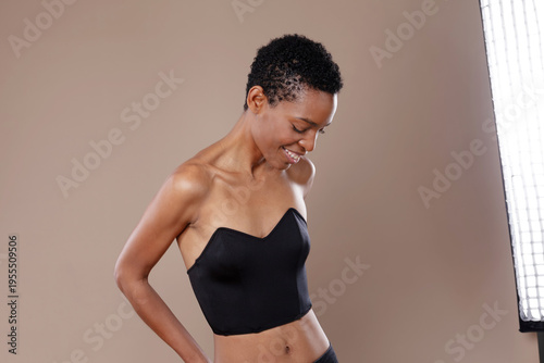 Smiling black woman with short hair posing in professional photo studio with lighting equipment
