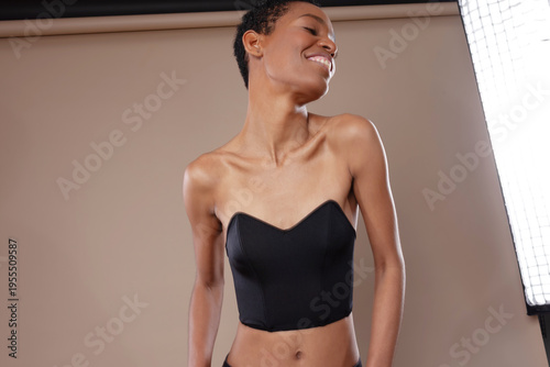 Smiling black woman with short hair posing in professional photo studio with lighting equipment