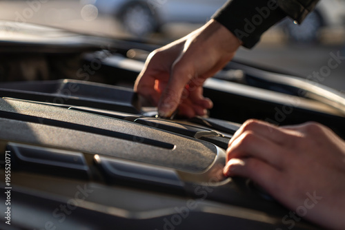 Hands closing engine cover under car hood, securing protective panel over motor components after inspection or maintenance.
