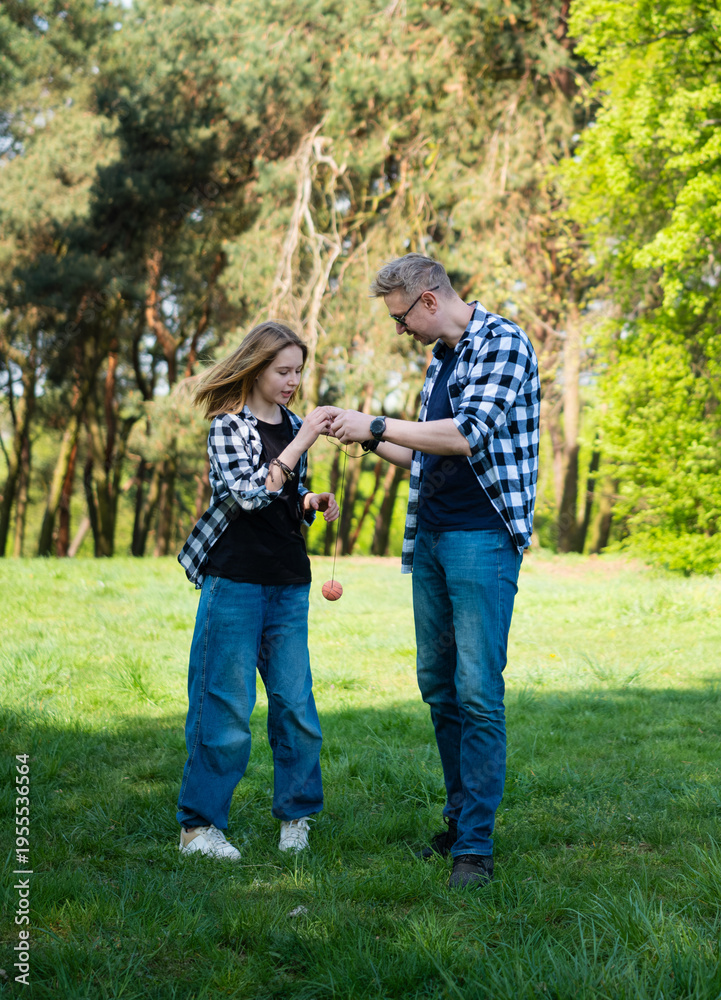 Fototapeta premium Father And Daughter Play With Yo-Yo Ball In Summer Park