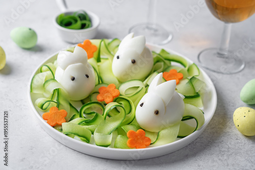 Boiled eggs in the form of rabbits with cucumber and carrots in a plate for Easter holidays