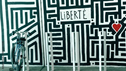 Parked Bicycle In Front Of Black And White Abstract Urban Background, text in French: Freedom