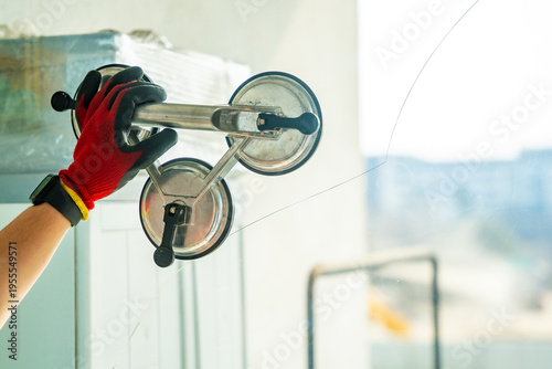 Worker attaching suction cup lifters to cracked window glass before removal from frame during replacement process in apartment. Professional window repair, safe handling, glass installation service