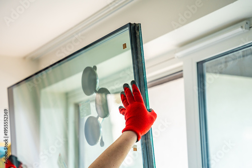 Photos Worker installing new triple glazed window glass unit into frame in apartment interior