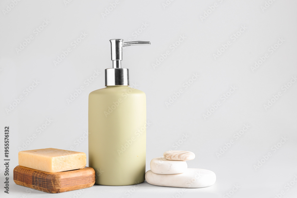 Obraz premium Soap dispenser with stones on white background