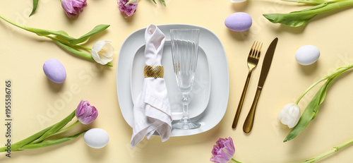 Table setting with Easter eggs and beautiful tulips on yellow background