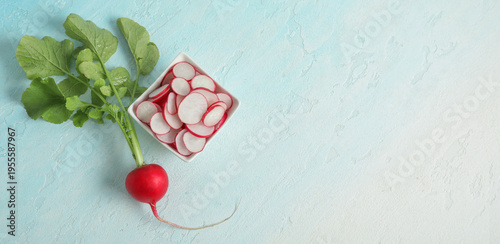 Bowl with slices of fresh radishes on light blue background
