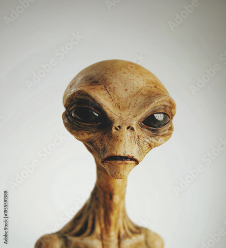 Yellow toned alien portrait with elongated neck and large eyes on soft neutral background