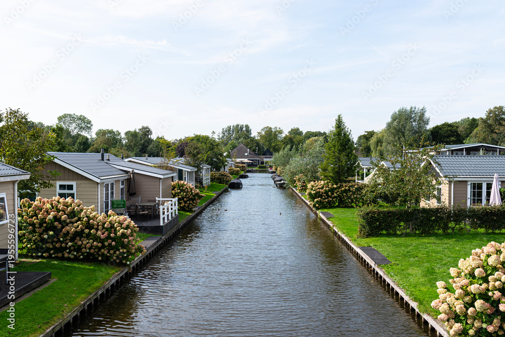 Fototapeta premium Giethoorn canal with holiday cottages, boats, and green lawns