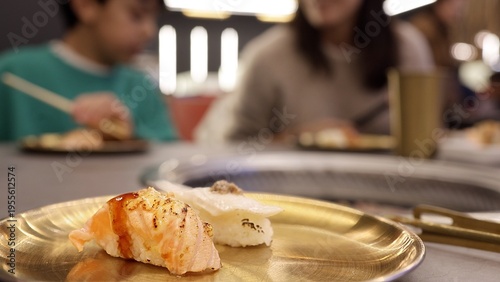Konstfotografi Fresh salmon nigiri and white fish sushi pieces placed on a golden plate, with p