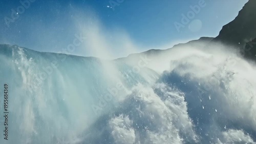 Powerful ocean wave crashing and with white foam and spray under a clear blue sky near dramatic