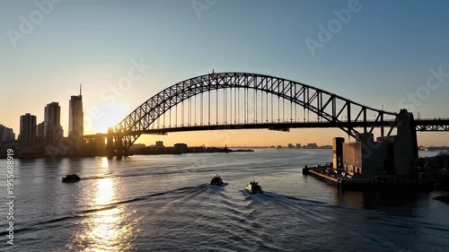 Sunrise over Sydney Harbour Bridge with commuter ferries sailing across the water towards the city