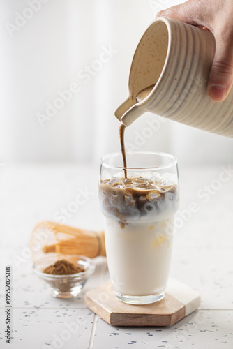 Preparing hojicha latte beverage. Iced  matcha latte tea. Vertical orientation.