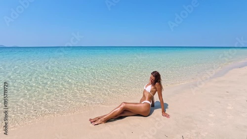 Woman in White Bikini Sunbathing on Tropical Beach by Clear Sea Water