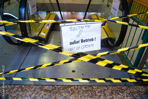 Mit gelb-schwarzem Absperrband gesicherte Rolltreppe, handgeschriebenes Schild „Rolltreppe außer Betrieb – Out of order“, Berlin, Deutschland