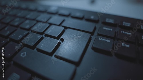 Extreme close up on finger pressing on enter or return key on computer keyboard. Person clicking on button to confirm or execute command or submit data. Dark room or office desk. Hacker or programmer