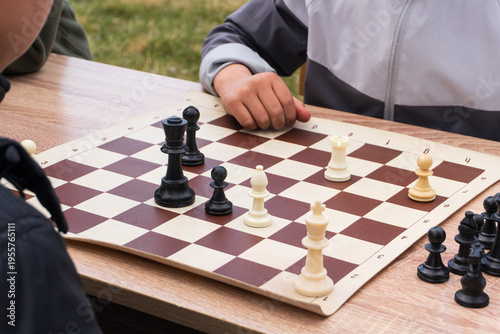 Fotografía Close-up of two people playing chess outdoors on a wooden table
