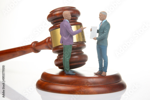 Miniature people at a court scene discussing a legal matter near a gavel on the table during a bright setting