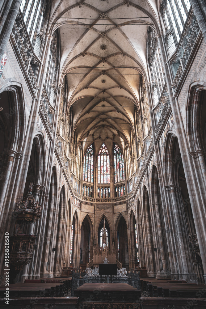 Obraz premium Visitors explore the gothic interior of St. Vitus Cathedral at Prague Castle. Tall arches and stained glass windows create a historic atmosphere in this famous location.