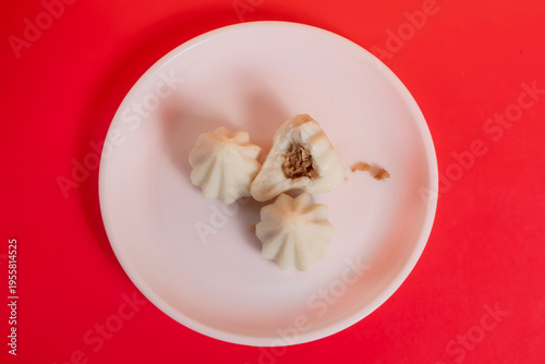 Steamed sweet modak rice dumplings on a white plate against a bright red background