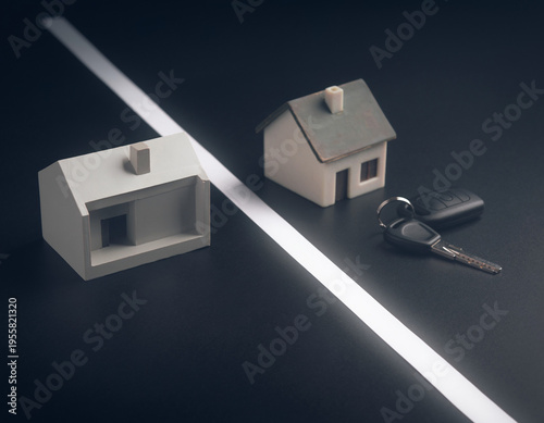 Concept of property division featuring house models and car keys, separated by a line on a dark surface, highlighting the distinction of ownership.