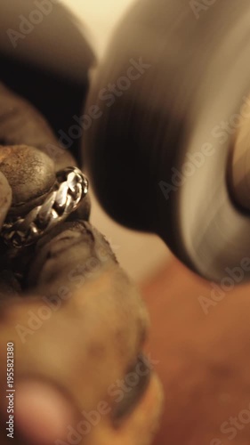 A person polishing a piece of jewelry with a blue and white polishing machine