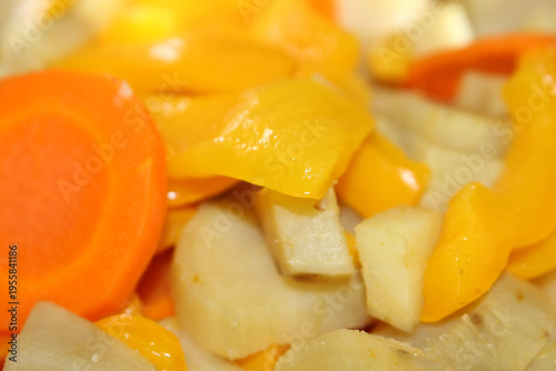 Cooked carrots with sweet potatoes and bell peppers. Healthy steamed mix of orange vegetables. Sliced boiled organic vegetables in a bowl. Cooked carrot, sweet potato and bell pepper.