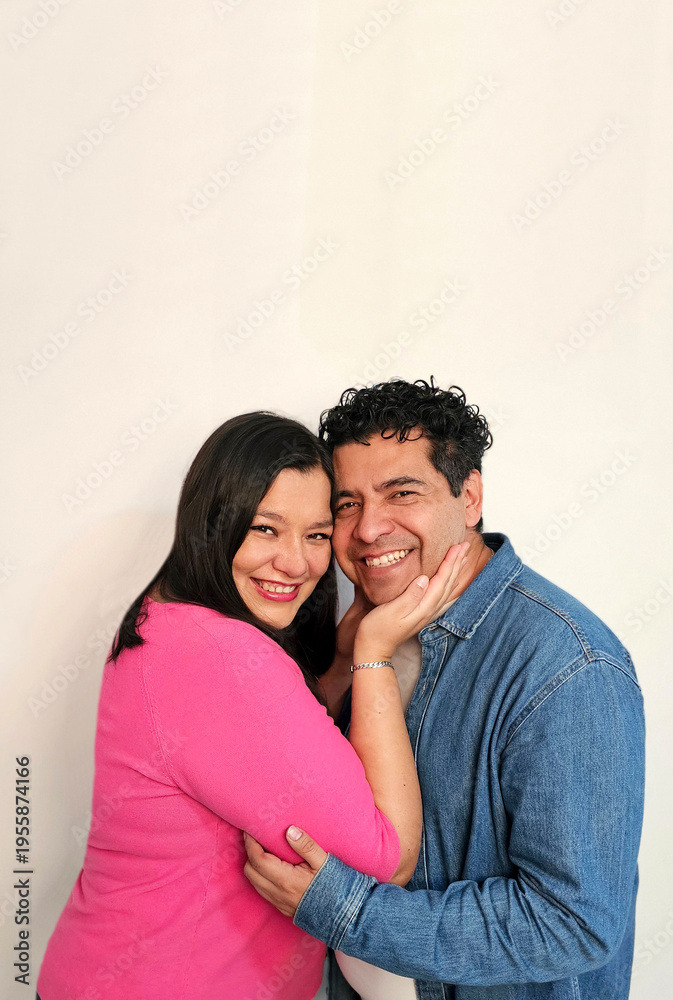 Fototapeta premium Latino man and woman in their 40s show their love to celebrate Valentine's Day and their anniversary with kisses and hugs, laughing and smiling