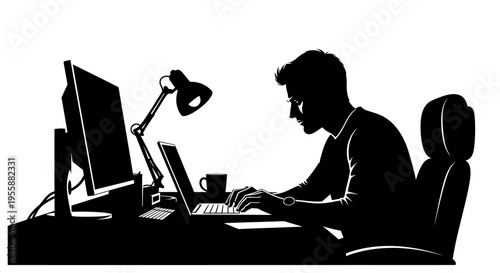 Silhouette of a man working on a laptop and computer at a desk with a lamp