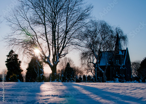 A winter scene at a cemetery with a church in the background.