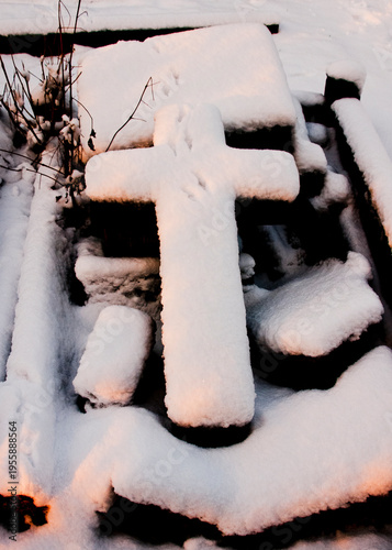 A snow-covered cross in a cemetery.
