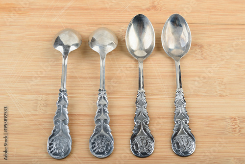 Four elegant vintage teaspoons arranged in a row on a wooden stand.