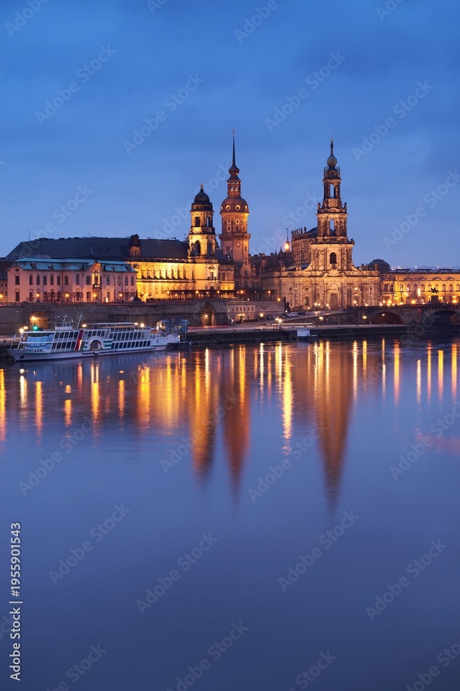 Obraz premium Katholische Hofkirche and Dresden Castle reflected across Elbe River at dusk