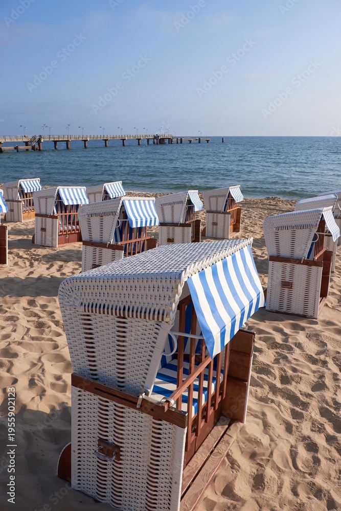 Fototapeta premium Strandkorb on Rugen beach with blue striped canopy and wooden pier