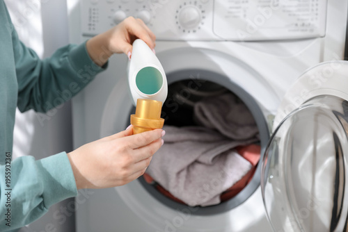Fotografie Woman adding detergent into washing machine at home, closeup