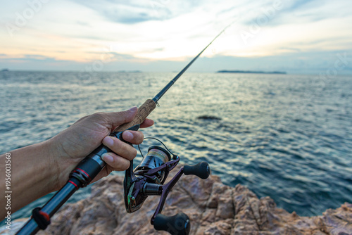 Man hand fishing on sea bay sea island sunset