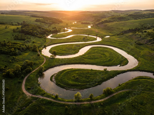 Serpentine river winding through lush green hills at sunset, aerial drone view.