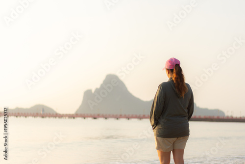 Rear view of woman watching sunrise on calm beach representing balance and tranquility