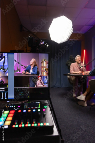 Obraz na płótnie Guest and host recording podcast or talk show, engaging in digital broadcasting, audio console and monitor showing camera angles, professional studio behind scenes